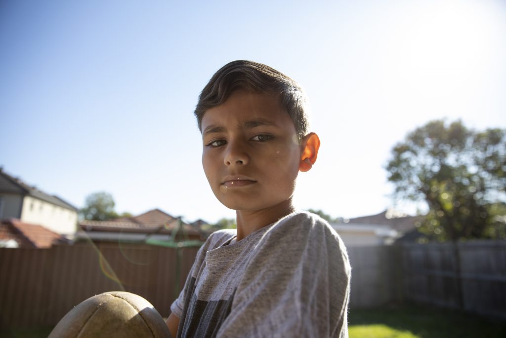 Portrait of Indigenous Australian aboriginal boy holding rugby ball